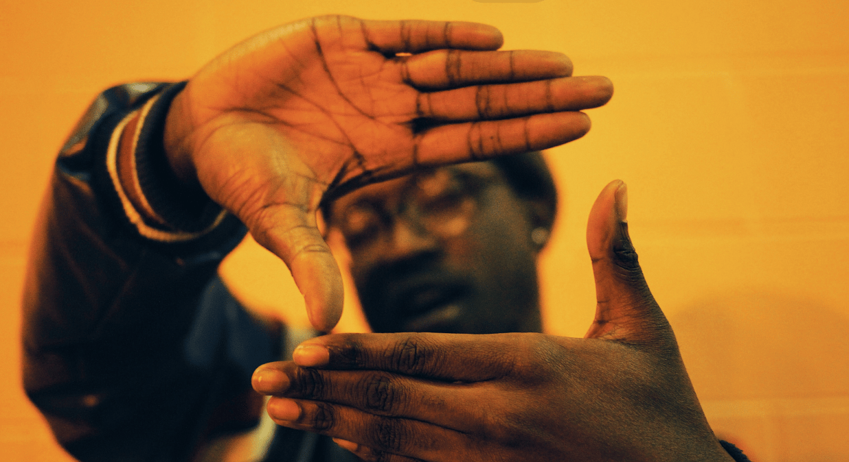 man making a square with his hands on a yellow background